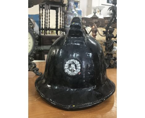 A black leather Fireman's helmet with helmet badge depicting old fire helmet