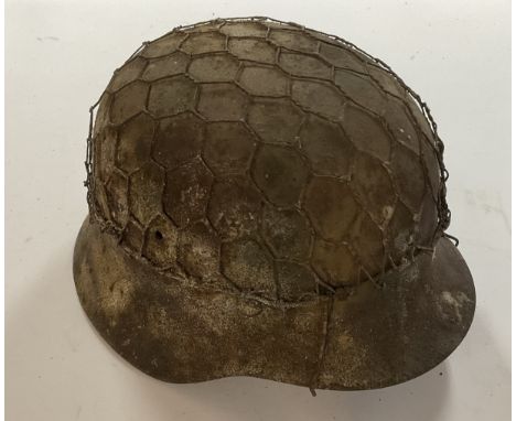 A WW1 German M16 infantry helmet with original camouflage paintwork,  mesh wire and liner.