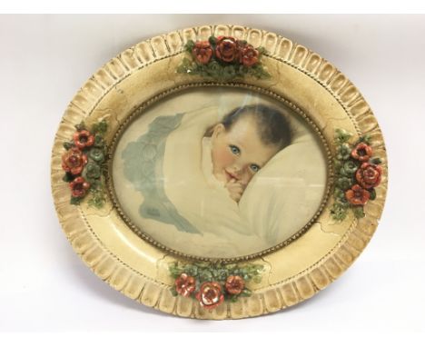 A Lilian Rowles print of an infant housed in a plaster oval shaped frame - NO RESERVE