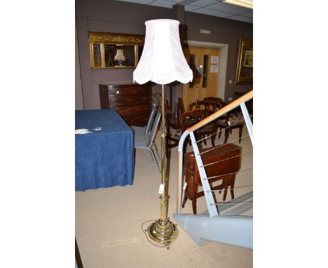 A 19th Century extending brass standard lamp on circular base with beadwork decoration and scrolling feet.