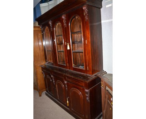 A reproduction Victorian style bookcase, with flared cornice of three arched double glazed panel doors, enclosing shelves sep