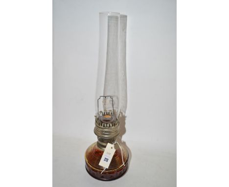 A Victorian oil lamp with tinted glass reservoir with moulded decoration, complete with glass chimney.