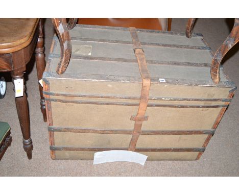 A cloth mounted wooden trunk with metal corners and central leather strap.
