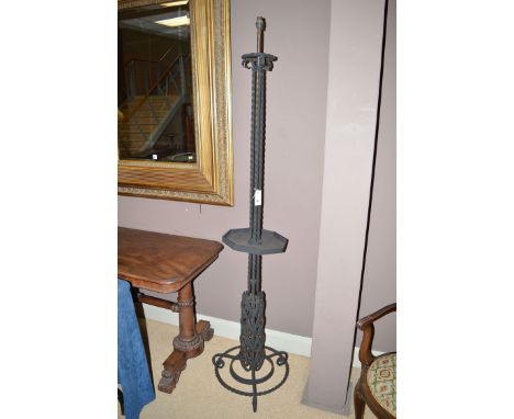 A wrought iron standard lamp with octagonal shelf and scrolling base.