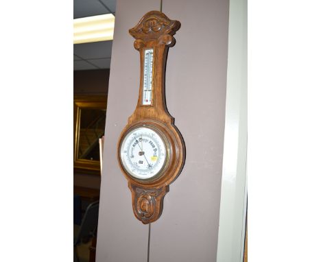 A first half 20th Century oak framed barometer with floral carving.