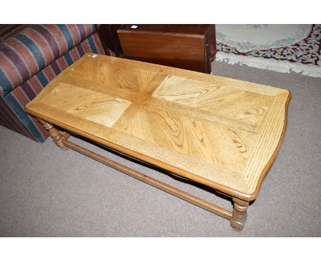 A light stained oak rectangular coffee table, raised on turned legs joined by square stretchers.