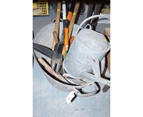 A collection of mainly gardening hand tools; a galvanised watering can; and a large oval galvanised container.