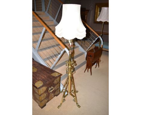 A Victorian extending brass standard lamp with copper mounts and scrolling design.