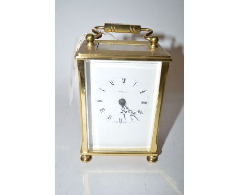 A Dominion brass carriage clock, with roman dial, raised on turned feet.