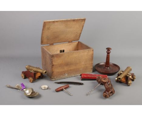 A wooden box of collectables. Includes pair of desk cannons, corkscrews, compass, razors and flatware etc.  