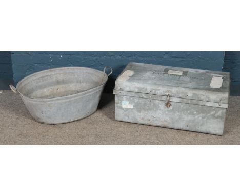 A tin bath tub along with a tin trunk.  