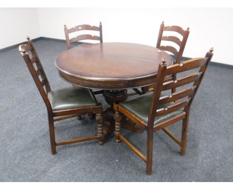 A heavy oak circular extending table on pedestal support and four ladder back chairs 