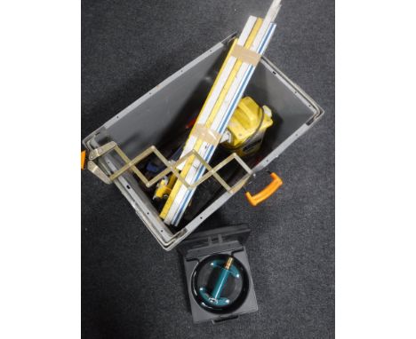 A box containing 110V transformer, spirit levels, pipe bender, socket sets etc