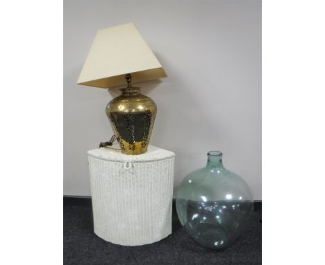 A glass carboy together with a loom linen box and a brass table lamp with shade