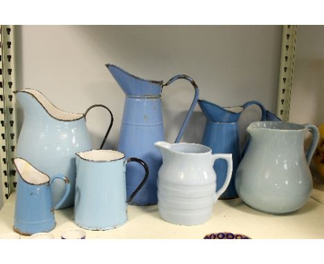Six blue enamel jugs and two pottery examples