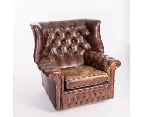 A brown leather button back wing armchair with studded arms   Condition Report:  Seat well worn, arms also with wear, scuff m