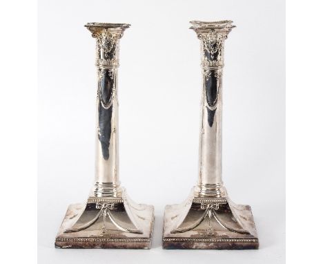 A pair of silver candlesticks, Thomas Bradbury, London, 1919 with decorative capitals and swags on square bases with beaded b