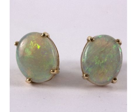 A pair of opal set earrings, oval cabochon stones to a yellow gold four claw mount