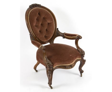 A Victorian walnut framed button back armchair with floral and scroll carving