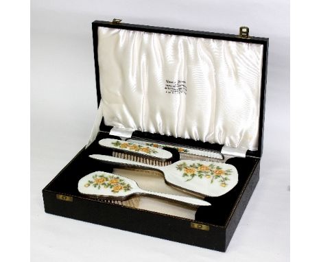 A four-piece silver and enamel dressing set, Birmingham 1961, the cream guilloché enamel painted yellow roses, cased within a