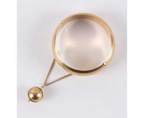 A hinged bangle, marked 18k, suspending a ball on chain, approximately 27.5gm