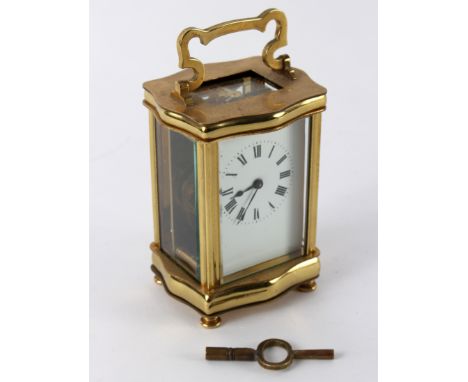 A gilt brass cased carriage clock of serpentine outline, the white enamel dial with Roman numerals, 15.5cm high handle up