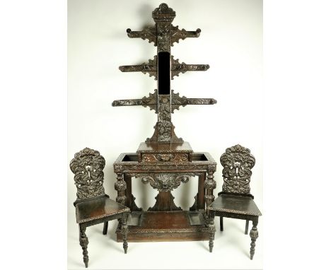 A very ornate late Victorian oak Hallstand, the triple cruciform back with various turned pegs and a centre mirror crested wi