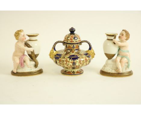 A pair of Royal Worcester porcelain&nbsp;Figures, each modelled with cherub holding an amphora vase, 12.5cms (5"); together w