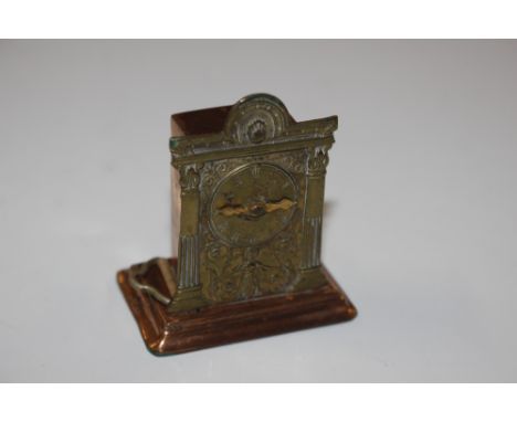 A copper and brass cased tape measure in the form of a mantel clock 