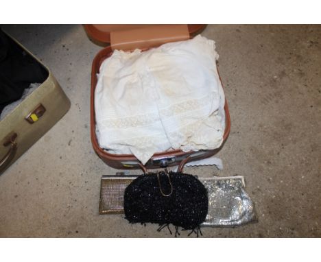 A case containing various evening bags and vintage baby's clothing 