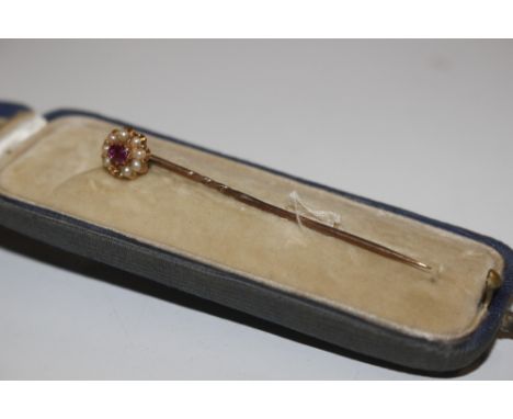 A cased yellow metal, ruby and seed pearl set tie pin (one stone missing)