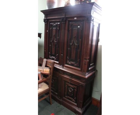 A Continental carved oak cabinet, with decorative panel cupboard doors over a base section with two inline drawers &amp; two 
