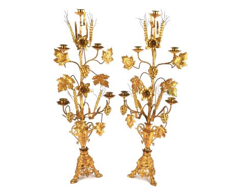 A pair of 20th century, gilt metal five branch candelabra, each cast with flowers and fruiting vines over a pierced triform b