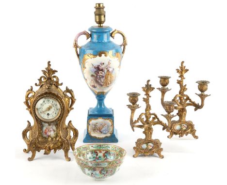 An early 20th century spelter clock with painted porcelain panels and a pair of two light candelabra, together with a Serve s