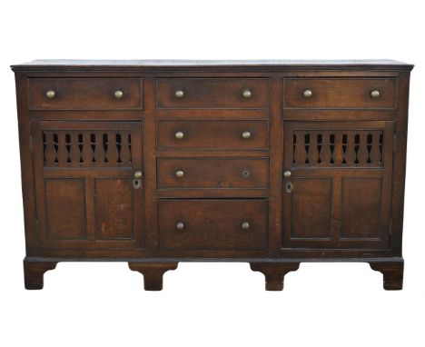 A George III oak dresser base, 1800s, Welsh, the six drawers enclosing a pair of pierced panel doors, on later bracket feet, 