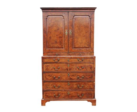 A George I burr walnut cabinet on chest, feather banded, the cavetto moulded cornice above a pair of arched panelled doors en