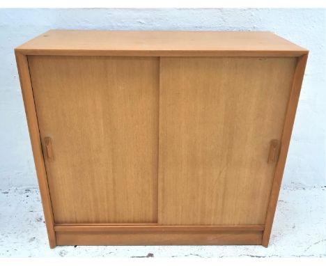 LIGHT MAHOGANY BOOKCASEwith a rectangular top above a pair of sliding doors with an adjustable shelf, standing on a plinth ba