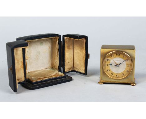 A MINIATURE TRAVELLING CLOCK in a folding leather case.