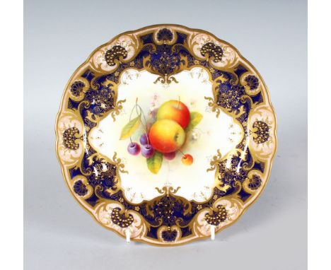 A ROYAL WORCESTER PLATE painted fruit under a heavily gilt and cobalt blue border by A. SHUCK, signed date code for 1929.