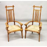 A PAIR OF ARTS & CRAFTS OAK ARMCHAIRS with spindle backs, cane seats and curving legs.