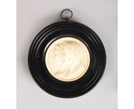 A GOOD EUROPEAN CARVED IVORY CIRCULAR PLAQUE, two classical Roman busts. 2,75ins diameter, in a wooden frame.