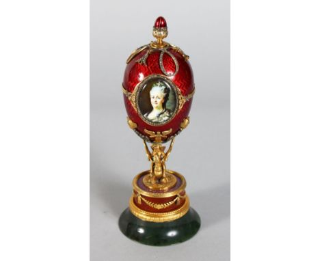 A SUPERB RUSSIAN RED ENAMEL AND SILVER GILT EGG with oval portrait of a lady and inset with diamonds, standing on a circular 