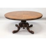 A VICTORIAN FIGURED WALNUT OVAL LOO TABLE, with quartered top, centre column ending in three curving
