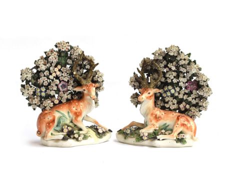A pair of 18th century Derby porcelain figures of recumbent stags, resting beneath flowering bocage, patch marks to base, eac