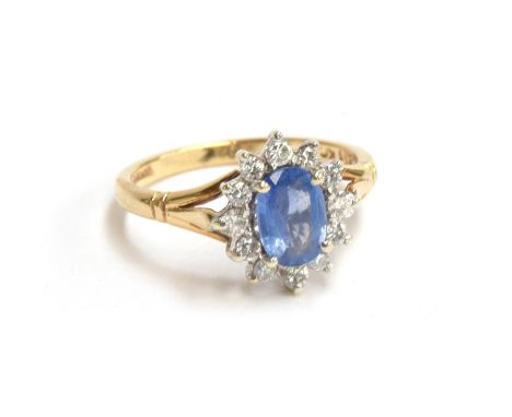 A Ceylon sapphire and diamond ring, sapphire approx 7x5mm in oval form surrounded by 12 brilliant cut diamonds on a 9ct gold 