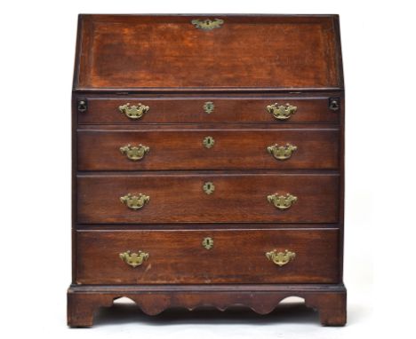 A George I/II oak bureau, fall front revealing a stepped fitted interior with drawers and pigeonholes and with a sliding well