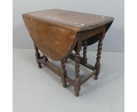 An early 20th century oak oval gate-leg drop-leaf table with barley twist supports. Width 91cm, height 74cm, depth 49cm.