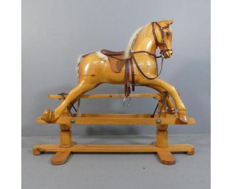 A hand carved pine rocking horse on stand, with horse-hair mane and tail. Lacking maker's label. Length 125cm, height 105cm, 