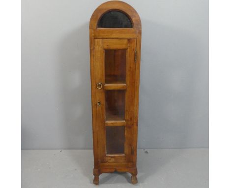 An Indonesian teak three tier display cabinet with arch top and glazed sides and door. Width 30cm, height 127cm, depth 31cm.