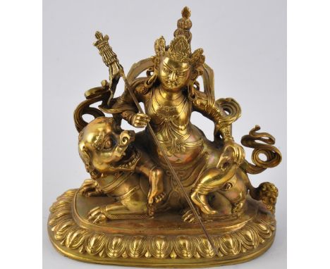 A Sino-Tibetan bronze figure of a Buddhist diety holding a staff and rat and seated upon a lion